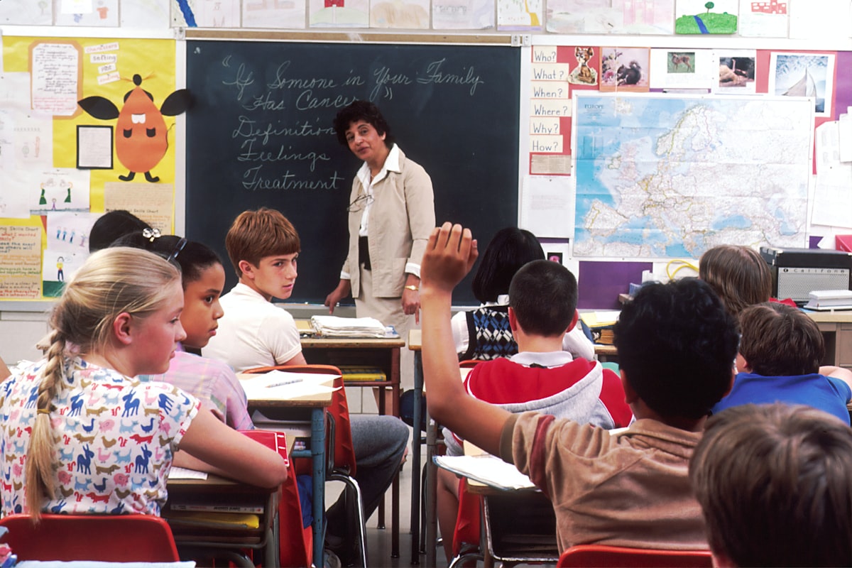 Teacher reviewing assessment papers at a classroom desk